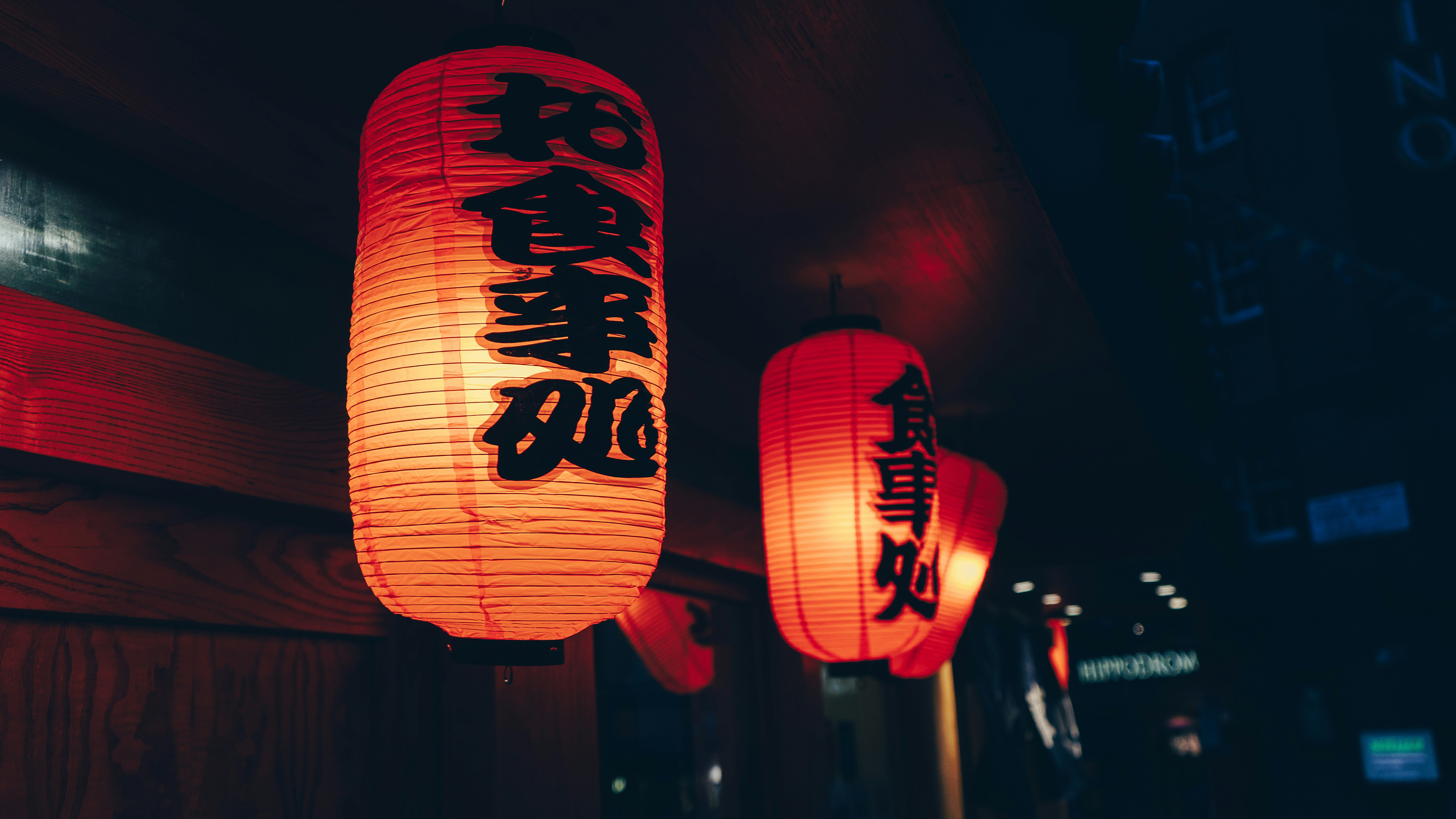 close-up photography of two orange paper lanterns with kanji script